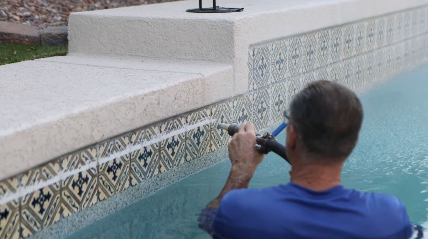 Pool technician cleaning tiles and removing calcium scale buildup